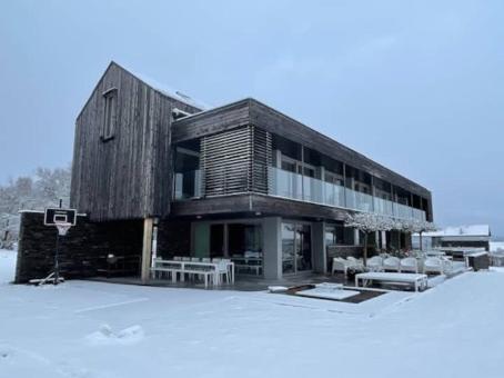 a large wooden building with benches in the snow at luxe vakantiehuis met panoramisch uitzicht Nisramont in La Roche-en-Ardenne