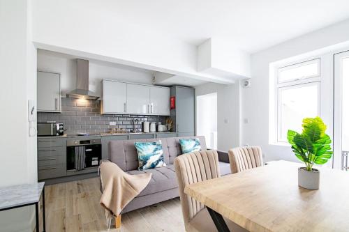 a kitchen and living room with a table and a couch at Modern 2 Bed Apartment with Patio Central Leicester in Leicester