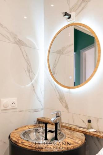 La salle de bains est pourvue d'un miroir rond et d'un lavabo. dans l'établissement Magnifique Appartement Pop Art Nancy, à Nancy