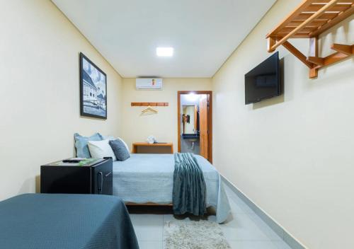 a bedroom with a bed and a flat screen tv at Hotel Santa Maria in Pirenópolis