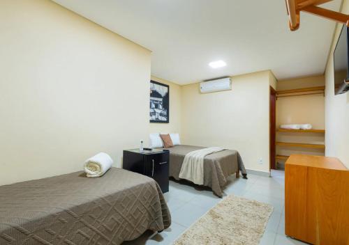 a hotel room with two beds and a tv at Hotel Santa Maria in Pirenópolis