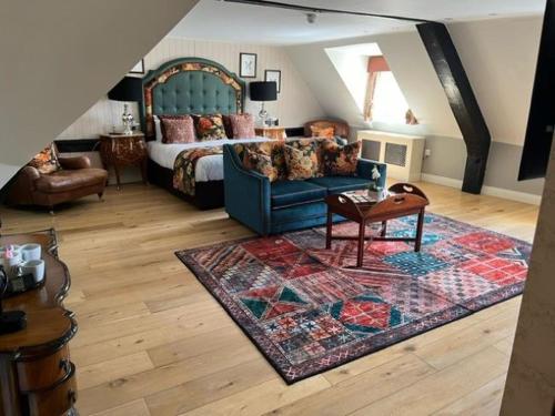 a living room with a bed and a blue couch at The White Horse Hotel, Romsey, Hampshire - The Coaching Inn Group in Romsey