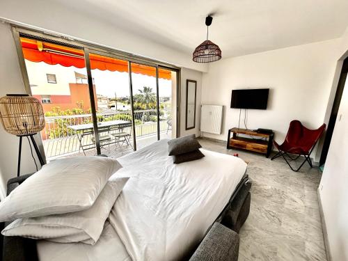 une chambre avec un lit et une grande fenêtre dans l'établissement Superbe studio, 200 m de la mer, climatisé avec terrasse et parking privé, à Cagnes-sur-Mer