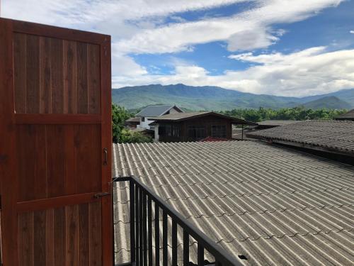 a wooden door on a roof with mountains in the background at แสนดีเพลส เกสเฮ้าท์ จอมทอง in Chom Thong