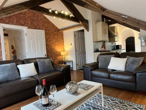 a living room with black leather couches and a table at Newcastle City Centre Loft Gem in Newcastle upon Tyne