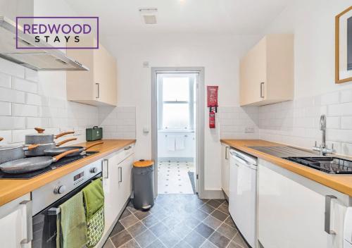 a kitchen with white cabinets and wooden counter tops at Comfortable and Homely 1-Bedroom 1-Bathroom Serviced Apartment with Free Parking, Free WiFi By Redwood Stays in Farnborough