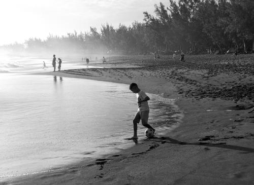 a boy playing with a soccer ball on the beach at Eskal Péi - Auberge de Jeunesse & Chambres d'hôtes in Étang-Salé