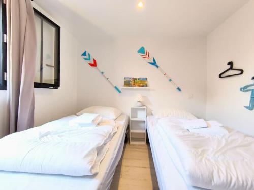 - 2 lits dans une chambre avec des cerfs-volants sur le mur dans l'établissement La Cabane C7, à Andernos-les-Bains