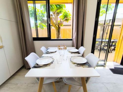 une table à manger blanche avec des chaises blanches et une fenêtre dans l'établissement La Cabane C7, à Andernos-les-Bains