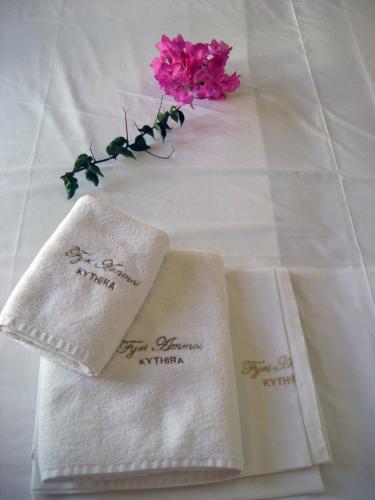 two white napkins with a pink flower on a table at Fyri Ammos Residences in Agia Pelagia