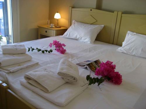 a white bed with towels and flowers on it at Fyri Ammos Residences in Agia Pelagia