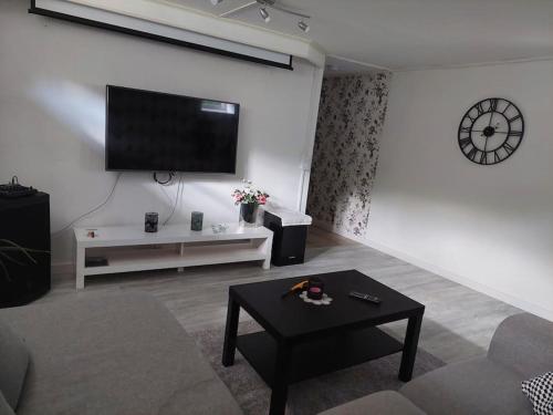 a living room with a couch and a tv on a wall at Fin lägenhet i Ulricehamn nära Lassalyckan in Ulricehamn