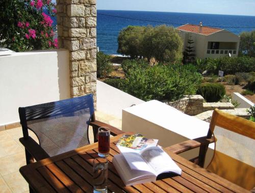 a wooden table with a book and a glass of wine at Fyri Ammos Residences in Agia Pelagia