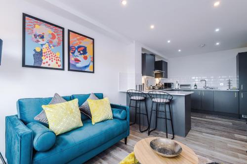 a living room with a blue couch and a kitchen at Charles House by Guestz in Preston