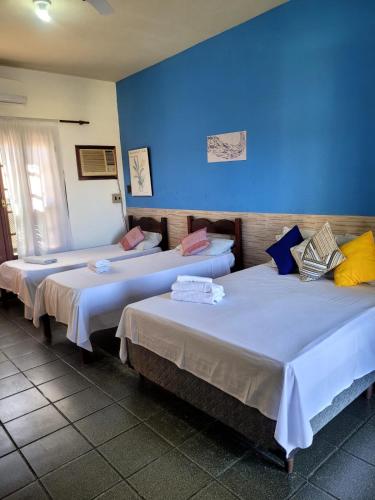 three beds in a room with a blue wall at Pousada Sol Nascente in Paraty