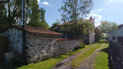 an old house with a stone wall and a driveway at Maison à la campagne in Les Brouzils