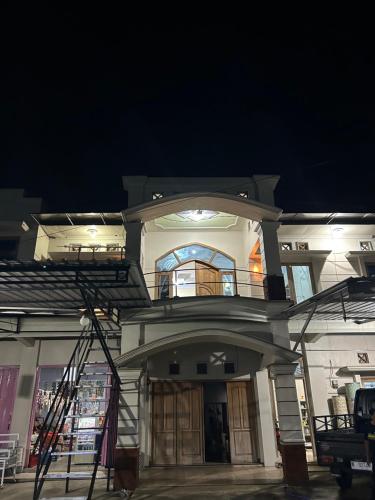 a large white building with a balcony at night at HARMONI GUEST HOUSE tumpak sewu in Sumberbopong