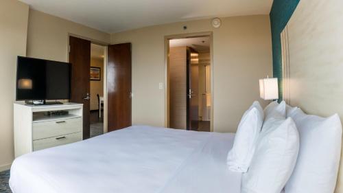 a hotel room with a white bed and a flat screen tv at Illinois Beach Hotel in Zion