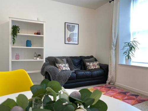 a living room with a black couch and a yellow chair at Quay Apartment with parking in Aberdeen