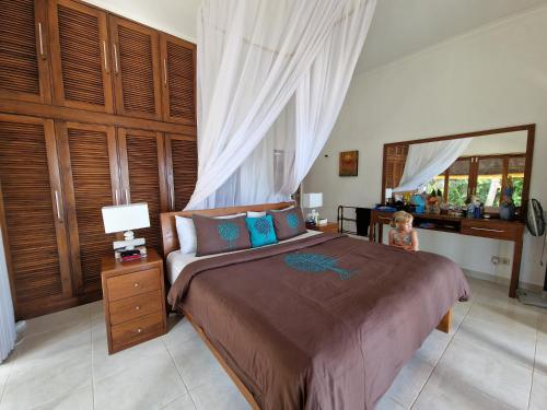 a child sitting on a bed in a bedroom at Villa Saffraan Bali in Banjar