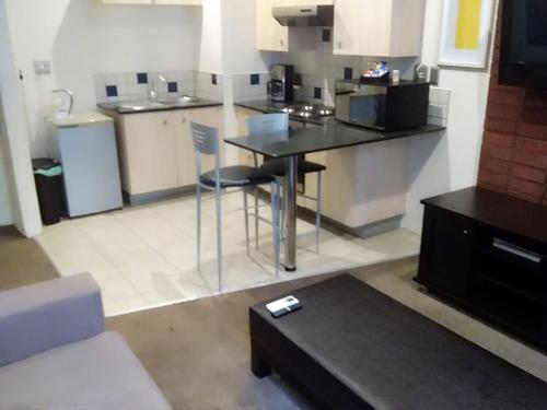 a living room with a table and a kitchen at Mabungubwe Hotel Apartments - Home Away from Home in Johannesburg