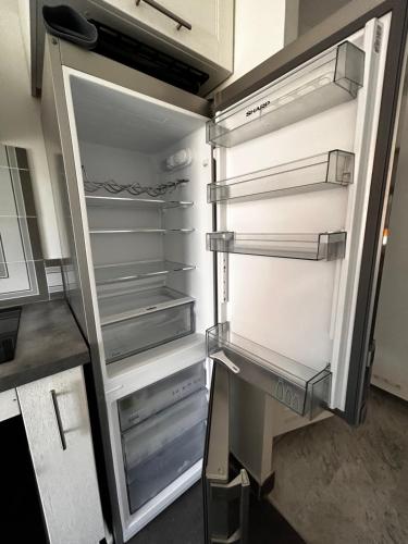 un réfrigérateur vide avec sa porte ouverte dans une cuisine dans l'établissement Superbe studio, 200 m de la mer, climatisé avec terrasse et parking privé, à Cagnes-sur-Mer