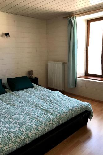 une chambre avec un lit avec une couette bleue et une fenêtre dans l'établissement Gite du Presbytère entre la Vôge les Bains et Vittel, à Gruey-lès-Surance