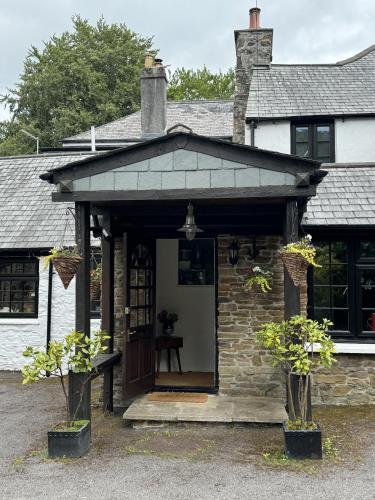 a stone house with a porch with a roof at Harrabeer Country House in Yelverton