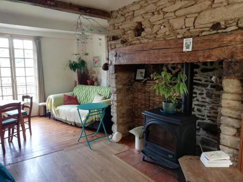 - un salon avec une cheminée en pierre et un canapé dans l'établissement Les oiseaux de passage, à Uzerche