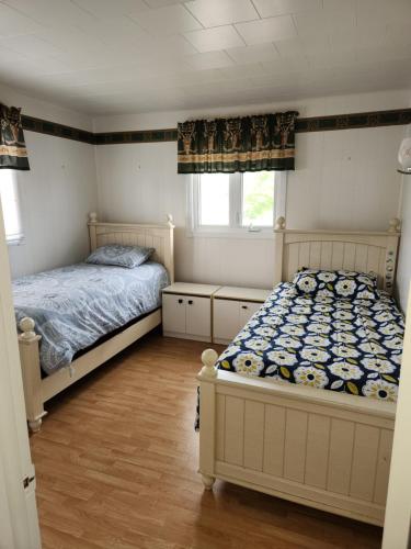a bedroom with two beds and two windows at Appartement de la rive in Shippagan