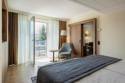 a bedroom with a bed and a chair and a window at Rogner Hotel Tirana in Tirana