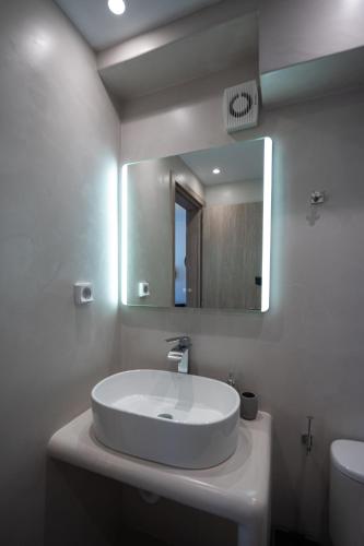 a white bathroom with a sink and a mirror at Grand Village in Imerovigli