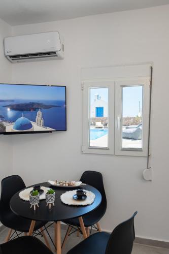 a dining room with a table and two windows at Grand Village in Imerovigli