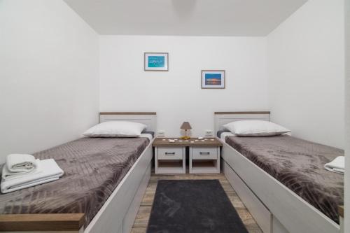two beds in a room with a side table at Apartment Lokvica in Omišalj