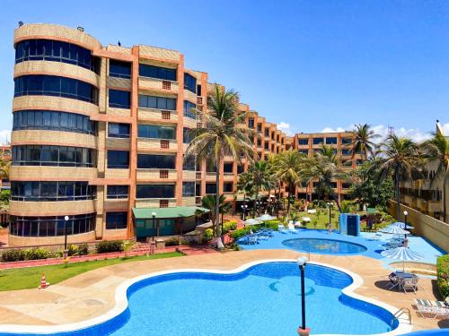 a resort with a large swimming pool in front of a building at Apartamento en tucacas Cocotero mar 2 con la playa a tus pies in Tucacas
