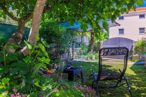 a chair in the garden under a tree at Apartment Lokvica in Omišalj
