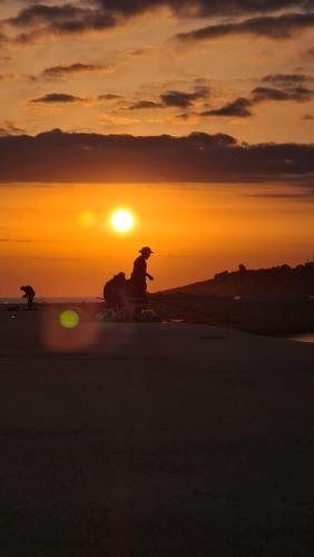 a person riding a bike in front of a sunset at VitaLenta Rooms & Apartments in Sciacca