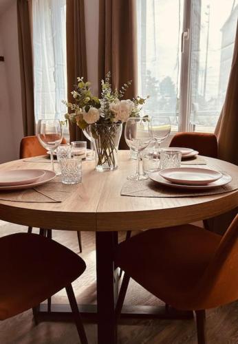 une table en bois avec un vase de fleurs et de verres dans l'établissement Cocon à 5 mn du circuit des 24h, au Mans