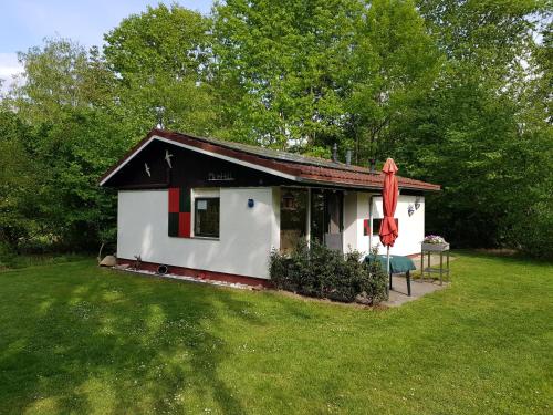 a small white house with a table and a red umbrella at MemHill in Exloo