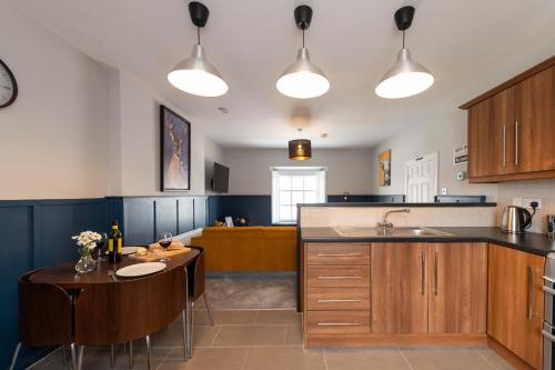 a kitchen with wooden cabinets and a table and a sink at Hamilton House Holiday Apartment in Killyleagh