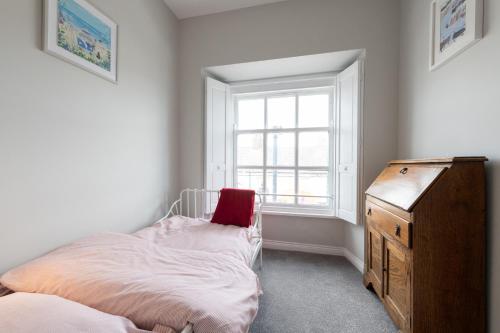 a bedroom with a bed and a dresser and a window at Hamilton House Holiday Apartment in Killyleagh