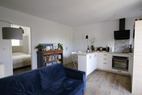 un salon avec un canapé bleu et une cuisine dans l'établissement Appartement avec terrasse privée, plage à pied, à Saint-Aubin-sur-Mer