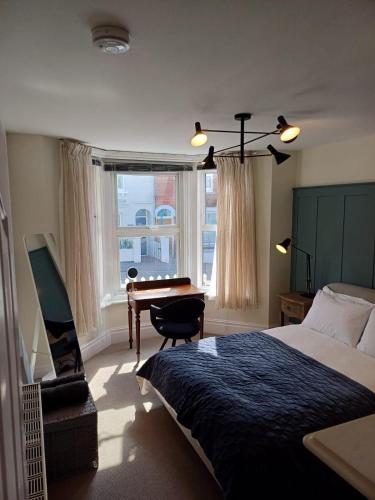 a bedroom with a bed and a desk and a window at Stylish 1 Bedroom Flat in Heart of Cowes in Cowes