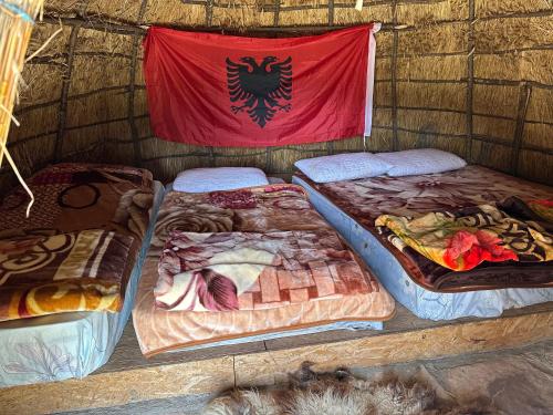 a group of beds in a room with a flag at Camping Lekdushi - Shehu in Tepelenë