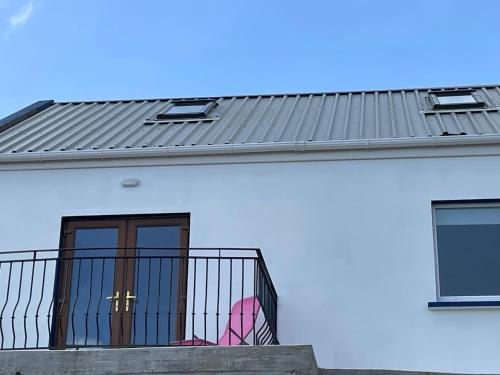 a white house with a black roof and a balcony at Seán Ógs House in Gortatlea