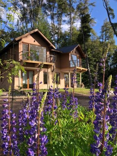 a house with purple flowers in front of it at CasaSur- 37Robles in Villa La Angostura
