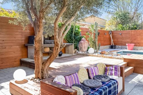 une terrasse avec un canapé à côté d'un arbre dans l'établissement Villa Moderne avec Piscine à Vinassan, à Vinassan