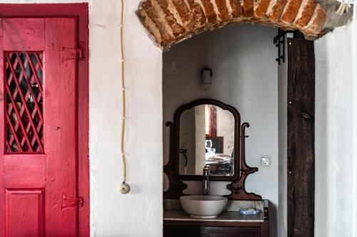 a bathroom with a sink and a red door at Casa do Pelourinho in Avis