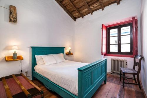 a bedroom with a green bed and a window at Casa do Pelourinho in Avis