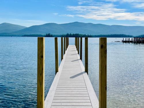 a dock on a lake with mountains in the background at Waters Edge Lodge in Lake George